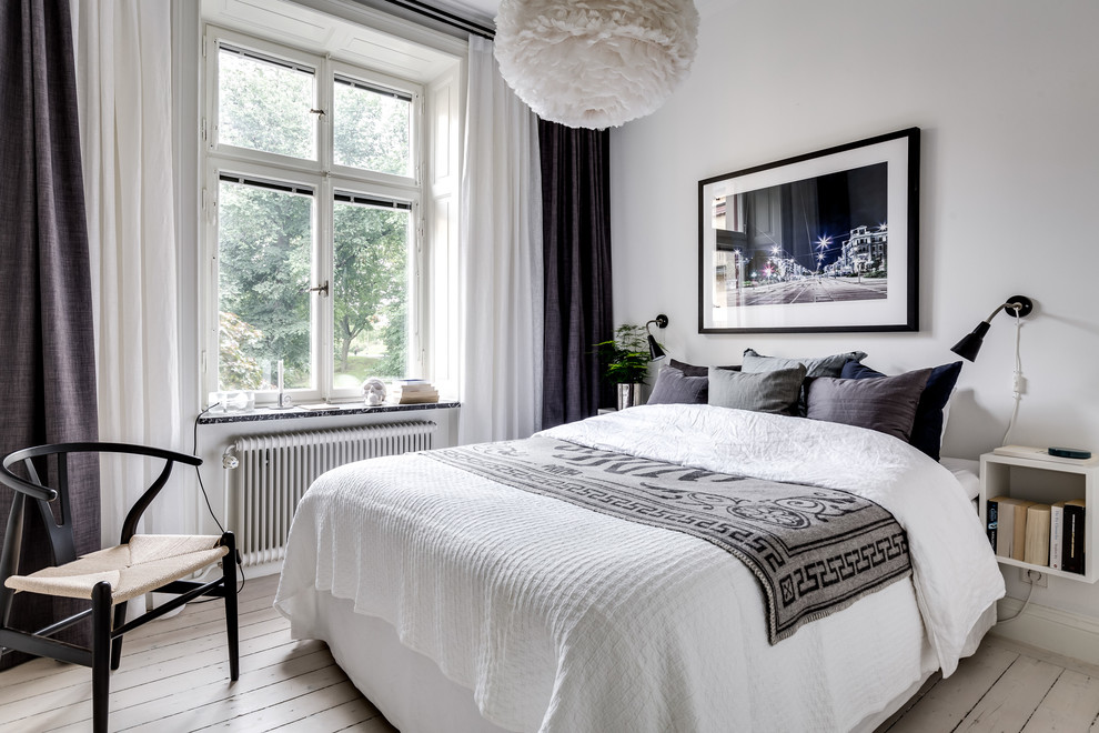 Photo of a mid-sized scandinavian master bedroom in Stockholm with white walls, painted wood floors and white floor.