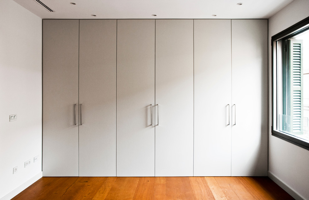 Photo of a modern dressing room in Palma de Mallorca with grey cabinets and medium hardwood floors.
