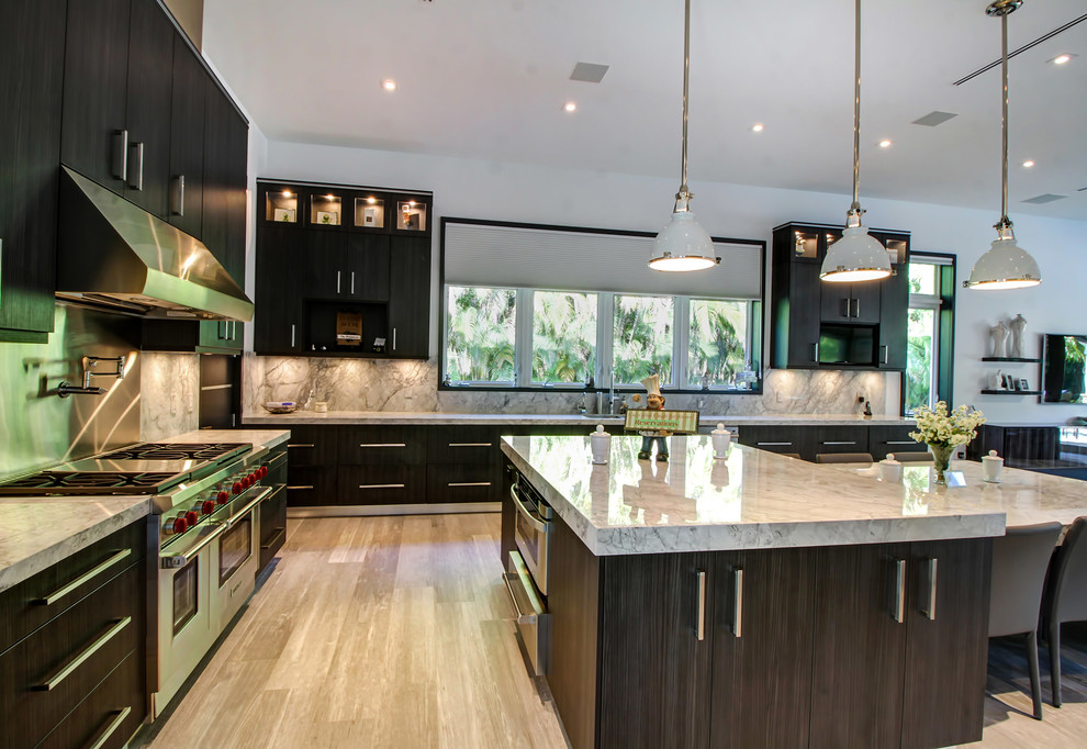 This is an example of an expansive transitional l-shaped separate kitchen in Miami with flat-panel cabinets, dark wood cabinets, marble benchtops, stainless steel appliances, multiple islands, an undermount sink, grey splashback, stone slab splashback and light hardwood floors.