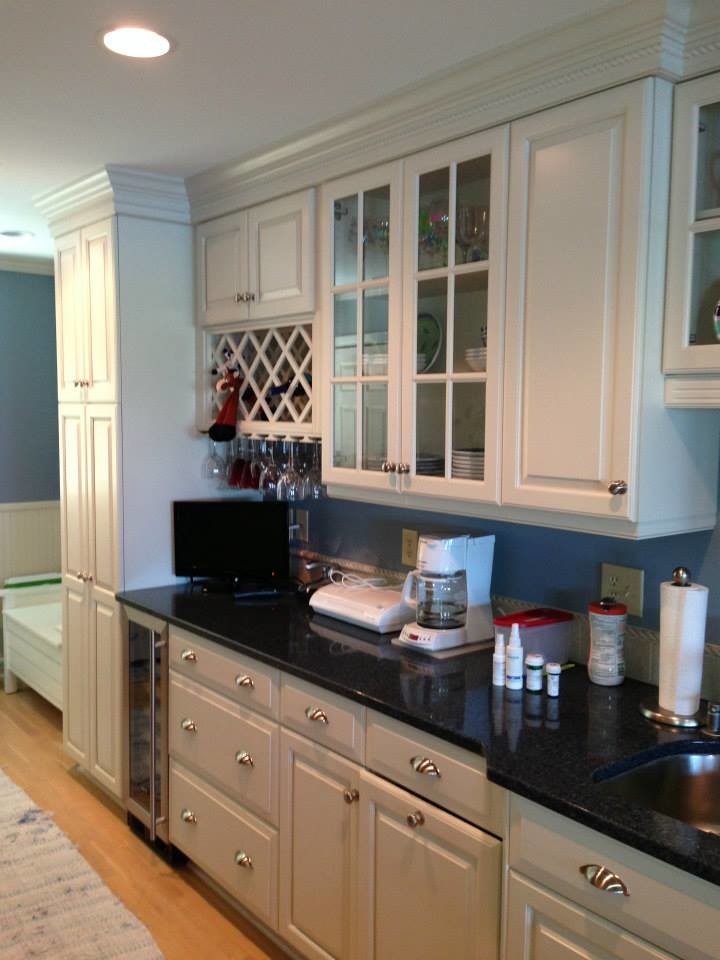 Example of a mid-sized single-wall medium tone wood floor eat-in kitchen design with a double-bowl sink, white cabinets, granite countertops, white backsplash, ceramic backsplash, stainless steel appliances and an island