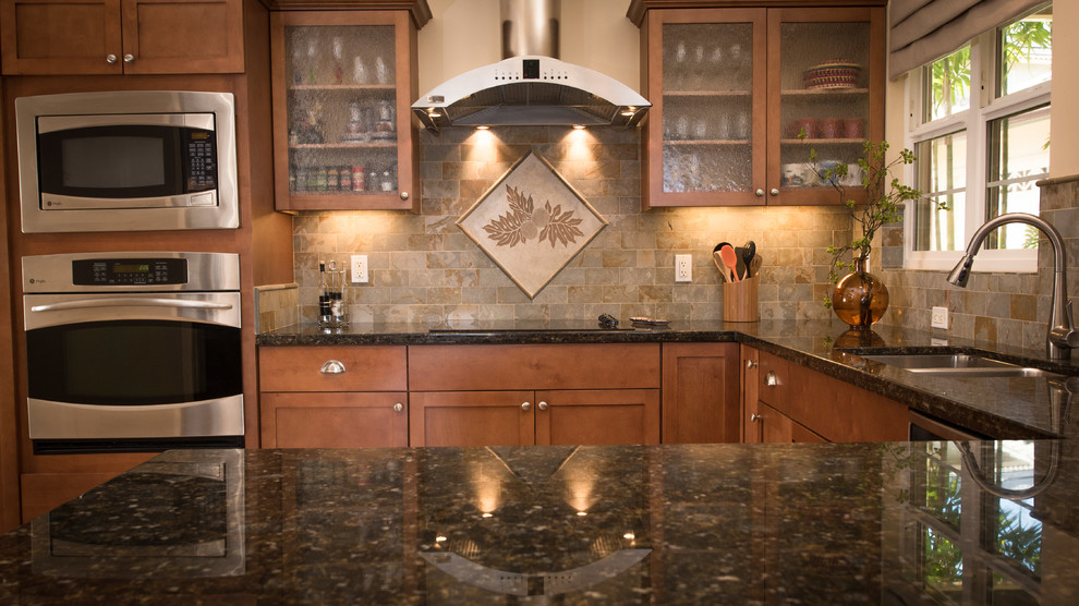 This is an example of a mid-sized traditional u-shaped eat-in kitchen in Hawaii with an undermount sink, shaker cabinets, medium wood cabinets, granite benchtops, beige splashback, ceramic splashback, stainless steel appliances and a peninsula.