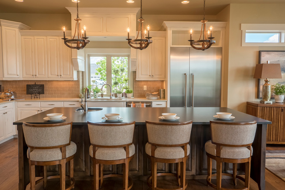 Inspiration for a large transitional l-shaped dark wood floor eat-in kitchen remodel in Boise with an undermount sink, raised-panel cabinets, white cabinets, solid surface countertops, beige backsplash, subway tile backsplash, stainless steel appliances and an island