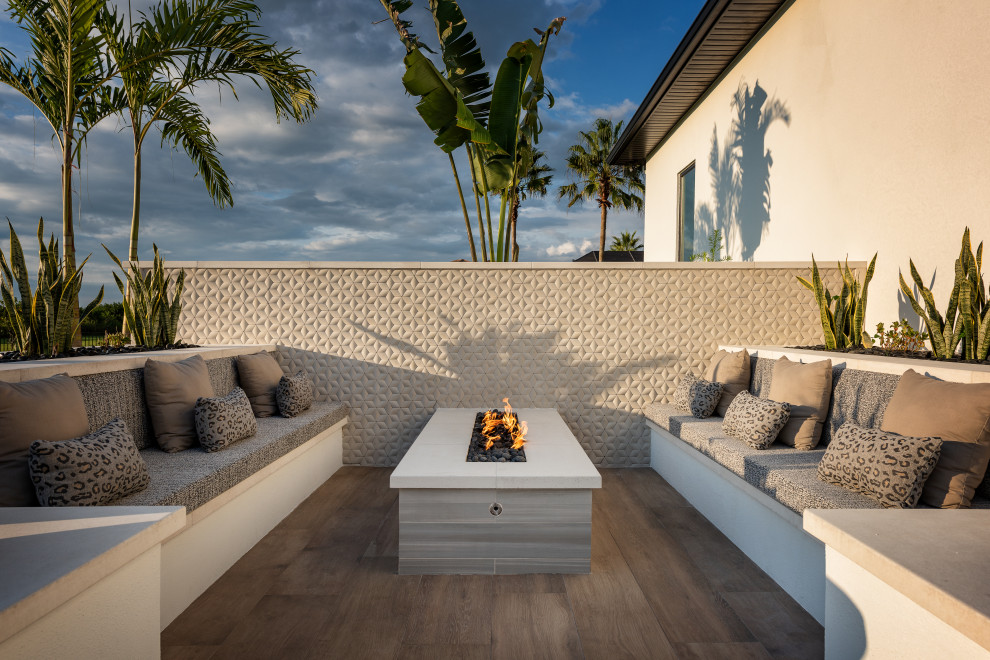Photo of an expansive modern backyard patio in Tampa with a fire feature, tile and no cover.