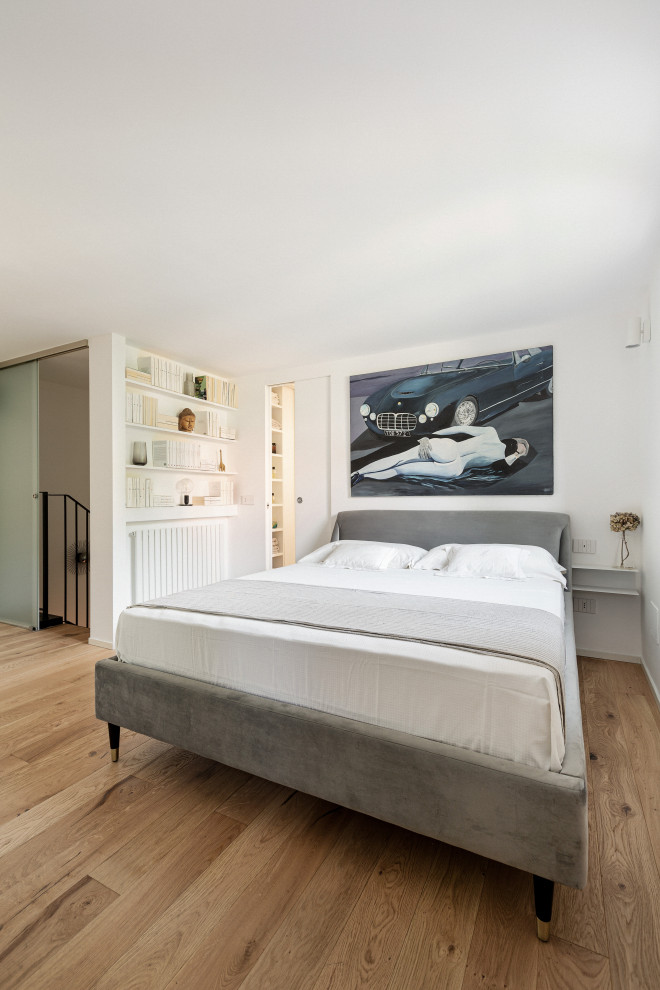 Inspiration for a mid-sized scandinavian master bedroom in Milan with white walls and light hardwood floors.