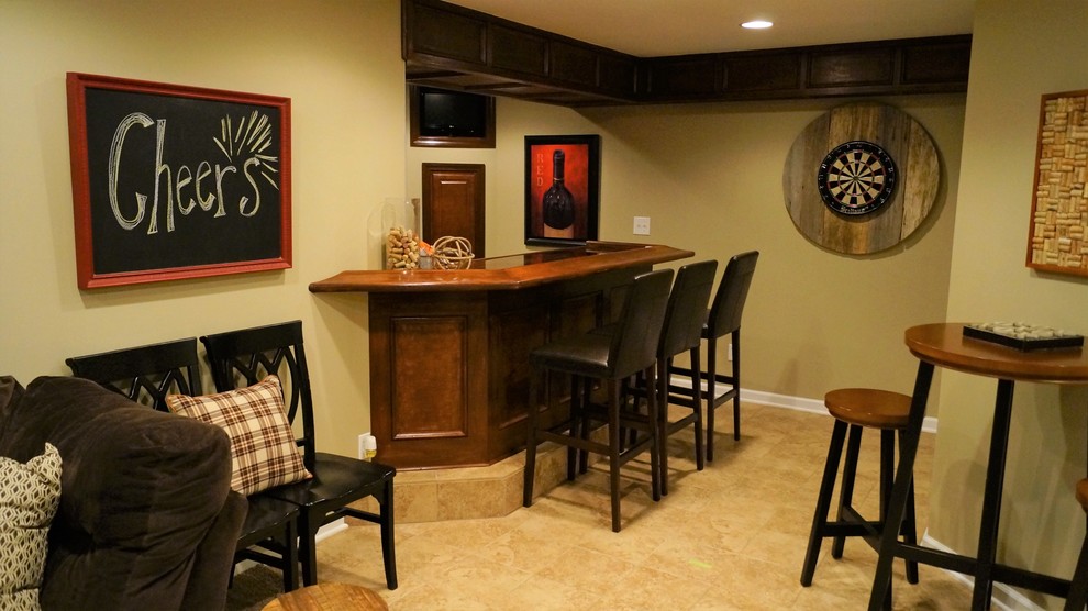 Photo of a small traditional l-shaped seated home bar in Columbus with recessed-panel cabinets, dark wood cabinets, copper benchtops, ceramic floors and beige floor.
