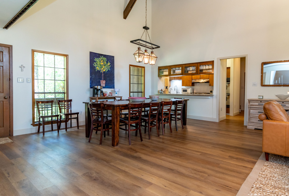 Inspiration for a large country open plan dining in New Orleans with vinyl floors, brown floor, exposed beam and white walls.