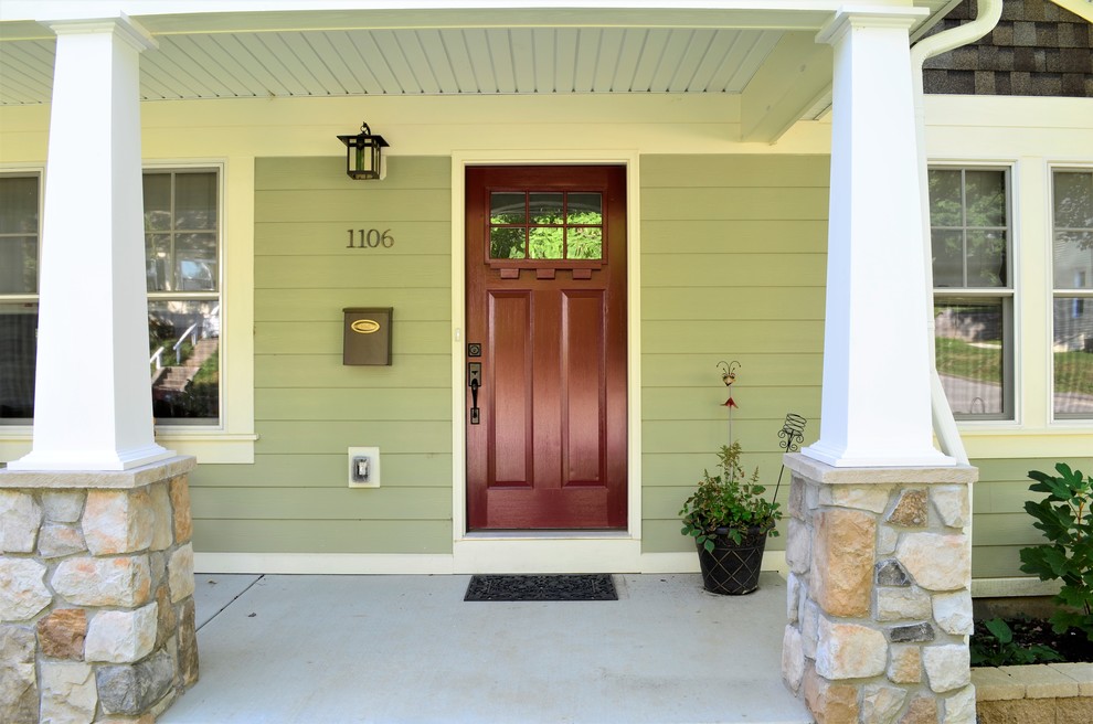 Photo of an arts and crafts front door in St Louis with green walls, concrete floors, a single front door and a medium wood front door.