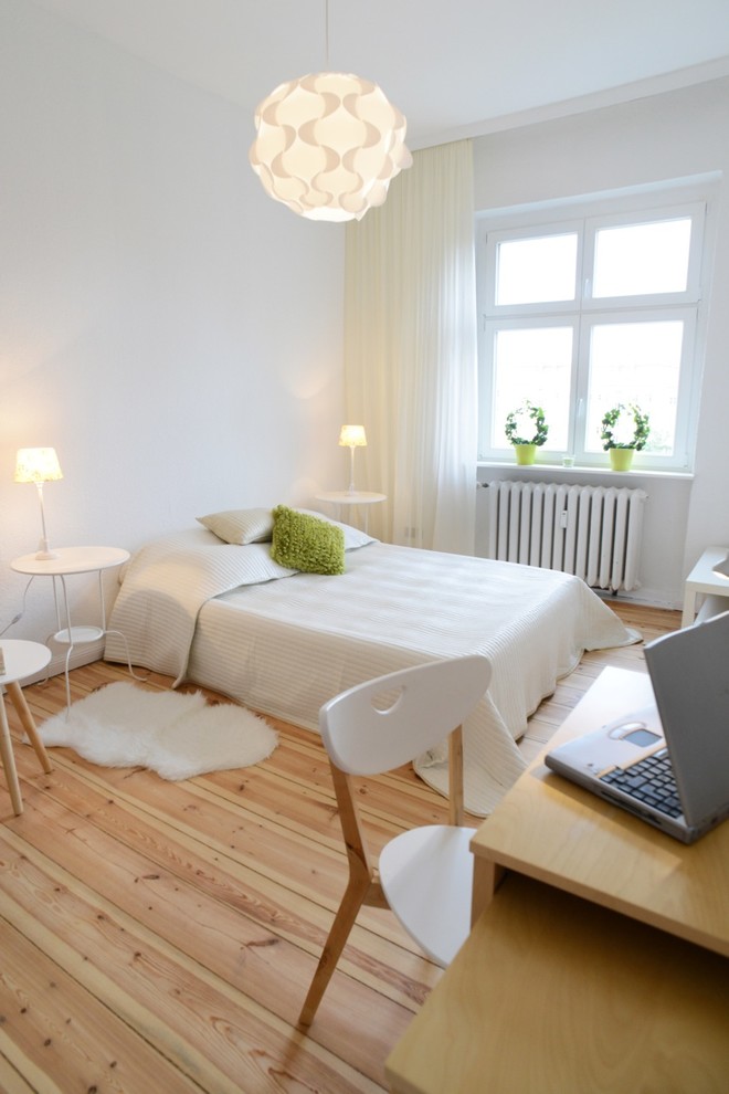 This is an example of a mid-sized contemporary master bedroom in Berlin with white walls, light hardwood floors and no fireplace.