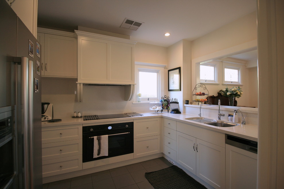 This is an example of an arts and crafts u-shaped separate kitchen in Melbourne with an undermount sink, shaker cabinets, white cabinets, quartz benchtops, porcelain floors, grey floor and white benchtop.