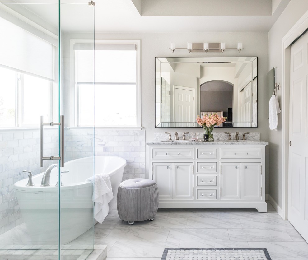 Mid-sized transitional master bathroom in Sacramento with shaker cabinets, white cabinets, a freestanding tub, white tile, marble, grey walls, marble floors, an undermount sink, marble benchtops, white floor, a hinged shower door and white benchtops.