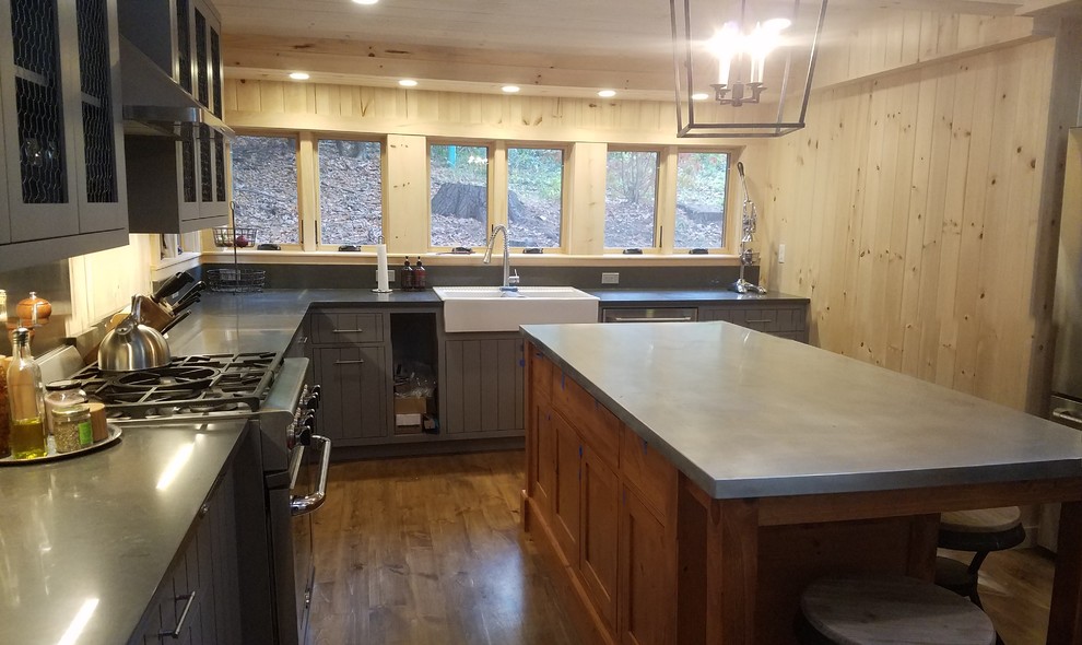 Mid-sized country u-shaped eat-in kitchen in Boston with a farmhouse sink, recessed-panel cabinets, grey cabinets, zinc benchtops, grey splashback, stainless steel appliances, dark hardwood floors and with island.