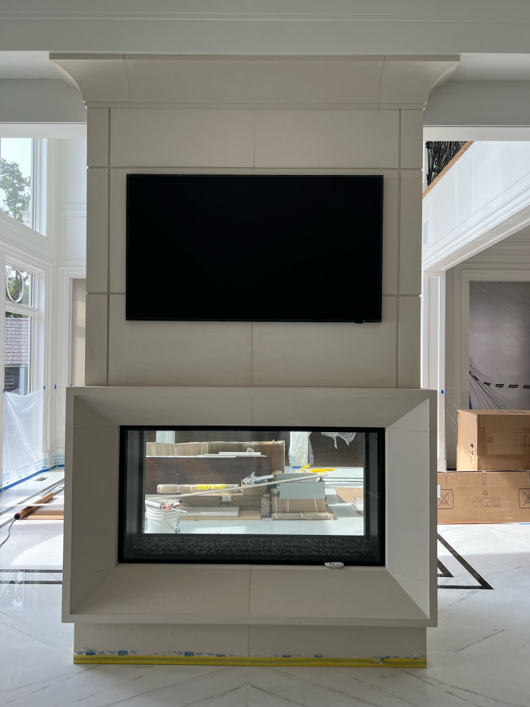 Идея дизайна: огромная парадная, открытая гостиная комната в стиле модернизм с бежевыми стенами, мраморным полом, двусторонним камином, фасадом камина из камня и белым полом без телевизора