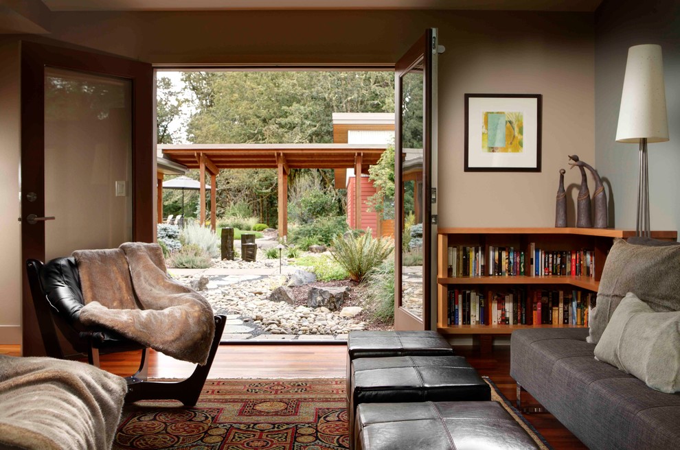 Photo of a mid-sized midcentury enclosed family room in Portland with a library, beige walls and medium hardwood floors.