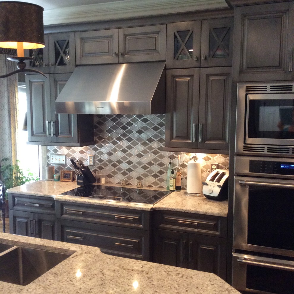 Example of a large transitional l-shaped medium tone wood floor eat-in kitchen design with raised-panel cabinets, dark wood cabinets, granite countertops, beige backsplash, ceramic backsplash, stainless steel appliances and an island