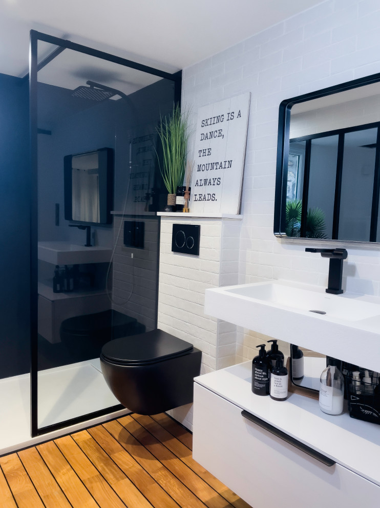 Idéer för ett mycket stort modernt vit badrum med dusch, med en kantlös dusch, en vägghängd toalettstol, vita skåp, vit kakel, tunnelbanekakel, vita väggar, ljust trägolv, ett konsol handfat och brunt golv