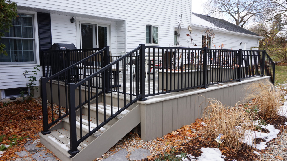 Diseño de terraza planta baja de tamaño medio sin cubierta en patio trasero con zócalos y barandilla de metal