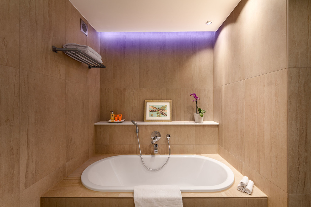 Großes Modernes Duschbad mit profilierten Schrankfronten, hellbraunen Holzschränken, Einbaubadewanne, Duschnische, Wandtoilette mit Spülkasten, beigen Fliesen, Steinfliesen, beiger Wandfarbe, Porzellan-Bodenfliesen, Aufsatzwaschbecken, gefliestem Waschtisch, beigem Boden, Schiebetür-Duschabtrennung und beiger Waschtischplatte in München