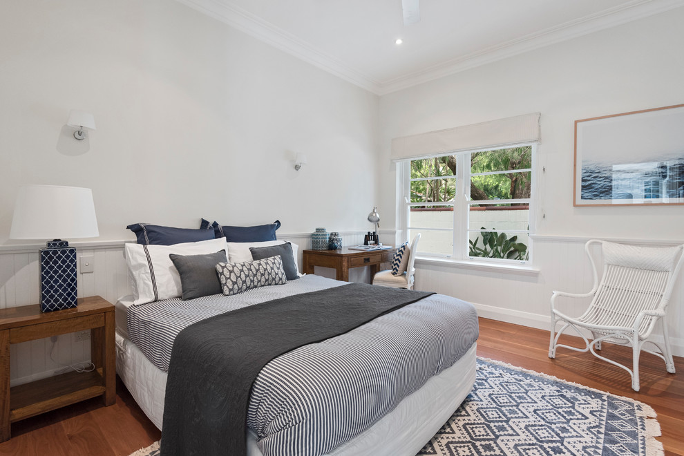 Mid-sized traditional bedroom in Sydney with white walls, medium hardwood floors and brown floor.