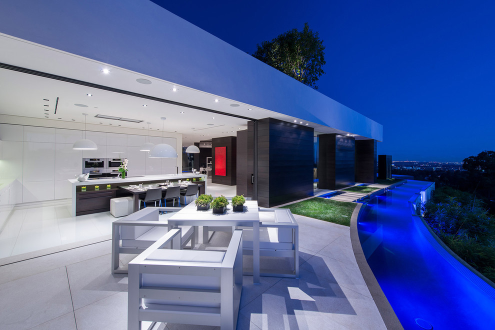 This is an example of an expansive contemporary side yard patio in Los Angeles with a water feature, tile and no cover.