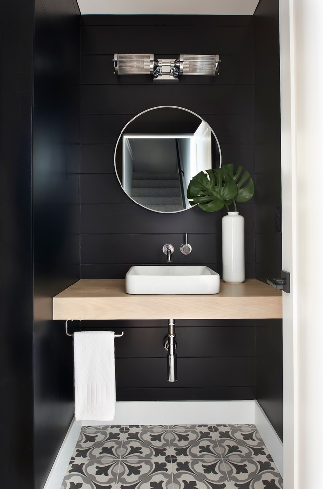 This is an example of a mid-sized transitional powder room in Denver with black walls, porcelain floors, a vessel sink, wood benchtops and multi-coloured floor.