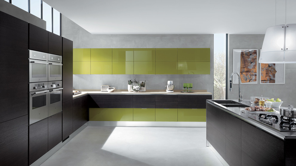 This is an example of a large modern u-shaped eat-in kitchen in Melbourne with a double-bowl sink, raised-panel cabinets, green cabinets, concrete benchtops, beige splashback, stone slab splashback, panelled appliances, porcelain floors and multiple islands.