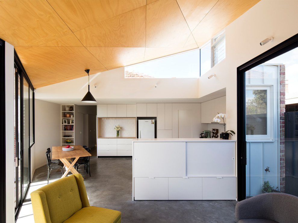 This is an example of a mid-sized modern kitchen in Melbourne with a single-bowl sink, light wood cabinets, concrete benchtops, white splashback, subway tile splashback, stainless steel appliances, concrete floors, with island and grey floor.