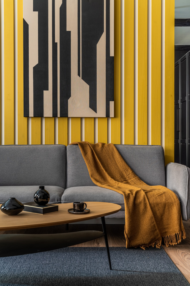 Пример оригинального дизайна: гостиная комната среднего размера в скандинавском стиле с желтыми стенами, зоной отдыха, бежевым полом, балками на потолке, деревянными стенами, акцентной стеной и полом из ламината