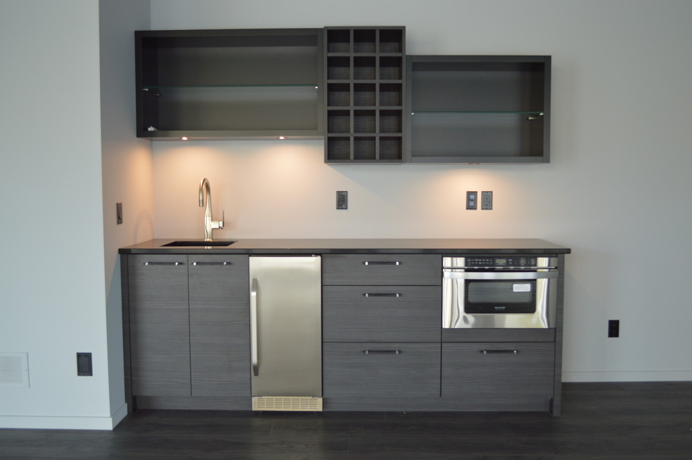 Inspiration for a mid-sized modern single-wall wet bar in Calgary with flat-panel cabinets, quartz benchtops and grey cabinets.