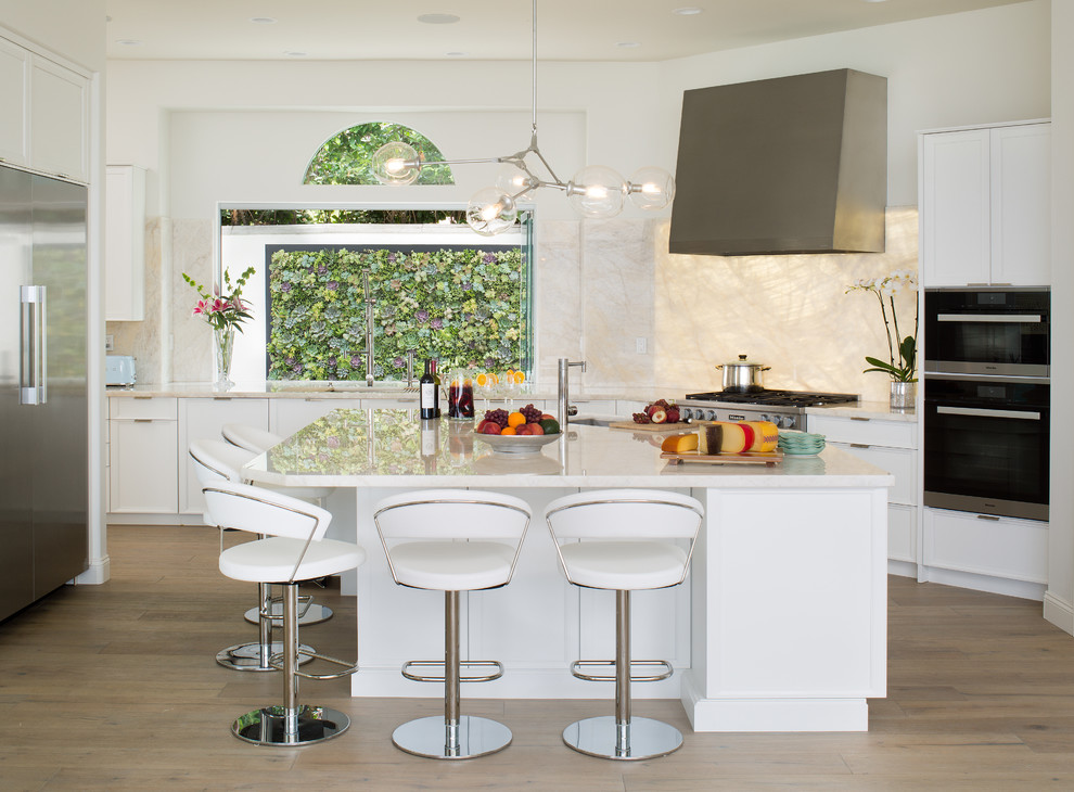 Inspiration for a large modern u-shaped kitchen in San Diego with a single-bowl sink, white cabinets, white splashback, stainless steel appliances, light hardwood floors, with island, grey floor, white benchtop, granite benchtops and granite splashback.
