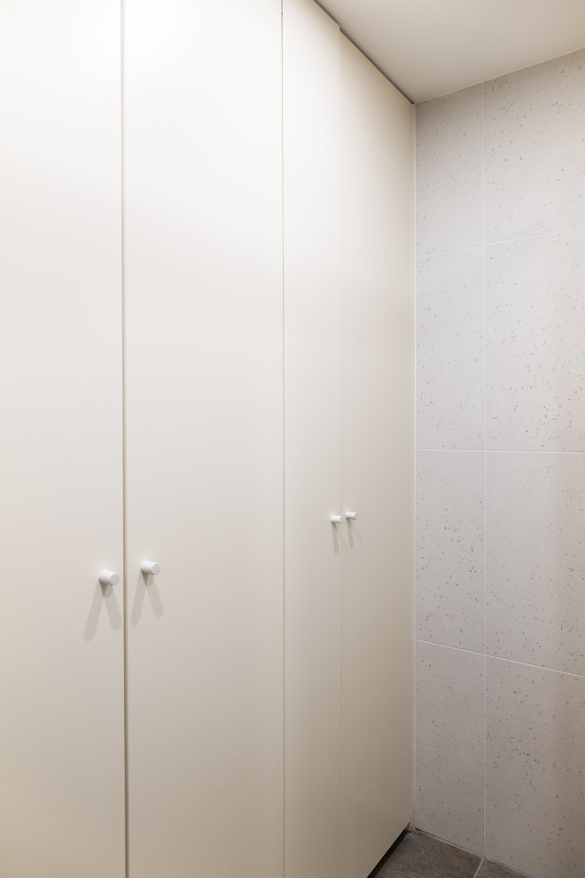 Foto di una piccola lavanderia multiuso con lavello integrato, ante a filo, ante beige, pareti beige, pavimento con piastrelle in ceramica, lavatrice e asciugatrice nascoste e pavimento marrone