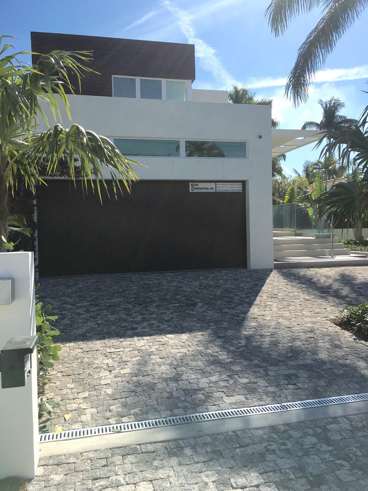 Photo of a mid-sized tropical front yard partial sun driveway in Miami with a garden path and concrete pavers.