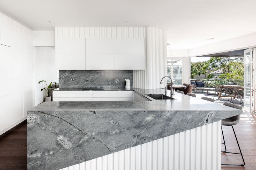 Inspiration for a contemporary u-shaped kitchen in Sydney with an undermount sink, flat-panel cabinets, white cabinets, grey splashback, panelled appliances, dark hardwood floors, a peninsula, brown floor and grey benchtop.