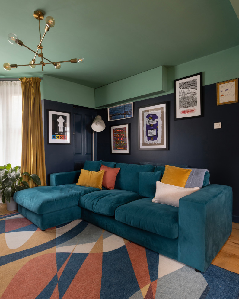 Mittelgroßes, Abgetrenntes Modernes Wohnzimmer ohne Kamin mit blauer Wandfarbe, braunem Holzboden, Eck-TV und braunem Boden in Sonstige