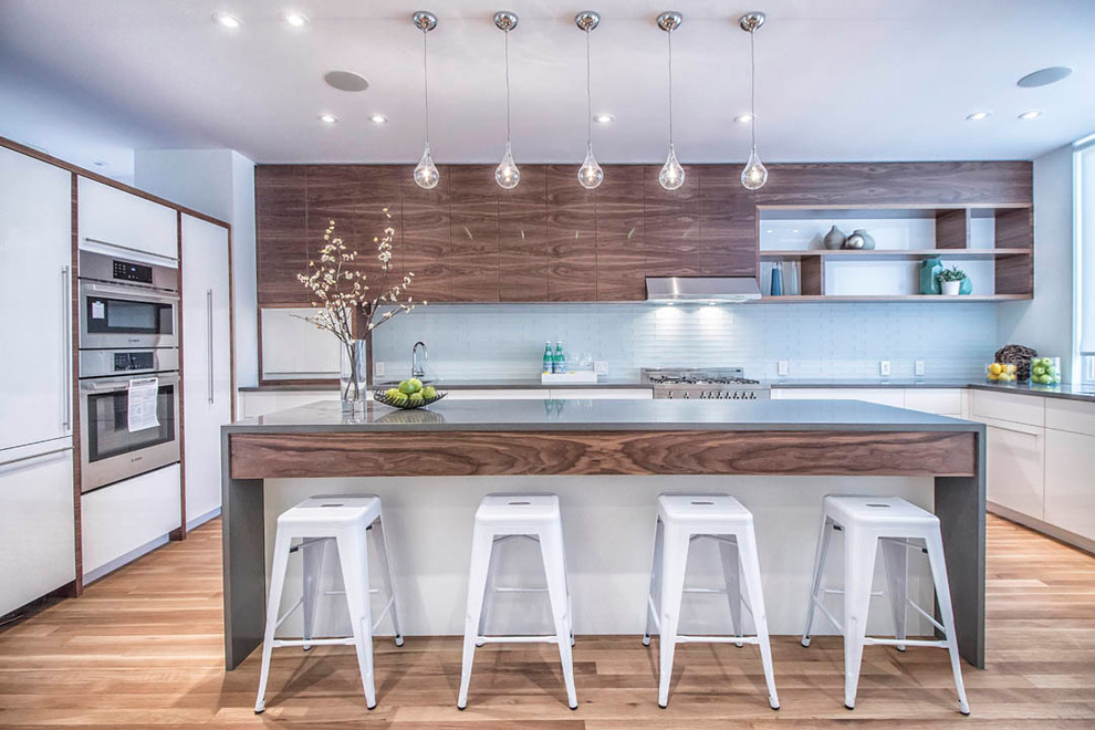 This is an example of a mid-sized contemporary l-shaped separate kitchen in Toronto with flat-panel cabinets, white cabinets, stainless steel appliances, with island, an undermount sink, concrete benchtops, blue splashback, light hardwood floors and glass tile splashback.