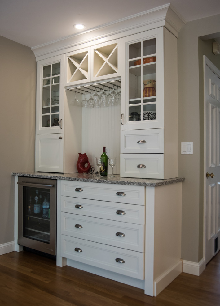 Inspiration for a mid-sized transitional l-shaped medium tone wood floor eat-in kitchen remodel in Boston with a farmhouse sink, shaker cabinets, white cabinets, quartz countertops, white backsplash, subway tile backsplash, stainless steel appliances and an island