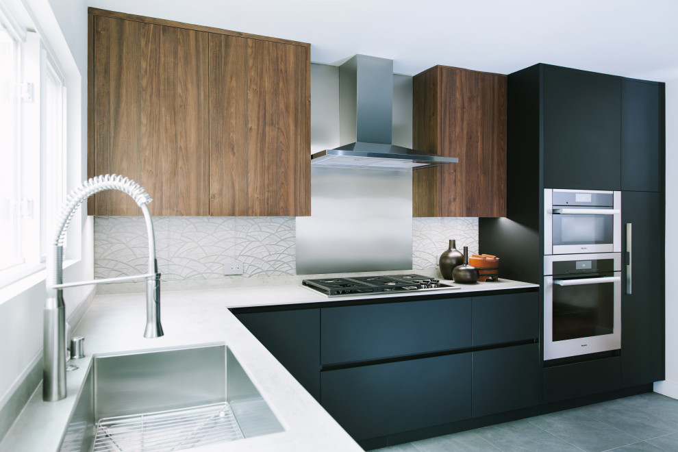 Mid-sized modern l-shaped eat-in kitchen in San Francisco with an undermount sink, flat-panel cabinets, black cabinets, grey splashback, stone tile splashback, stainless steel appliances, porcelain floors, a peninsula, grey floor and grey benchtop.