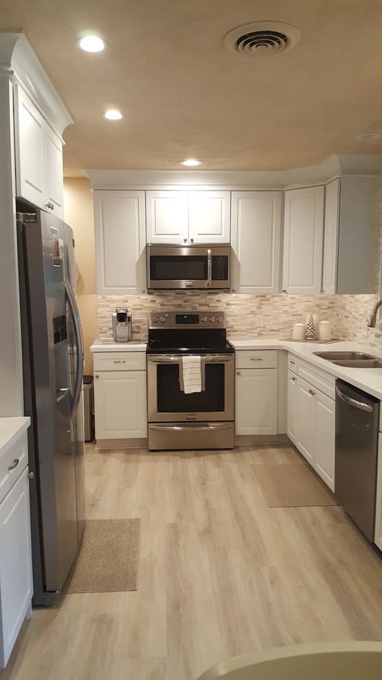 Inspiration for a small l-shaped eat-in kitchen remodel with an undermount sink, raised-panel cabinets, white cabinets, quartz countertops, white backsplash, porcelain backsplash, stainless steel appliances and no island