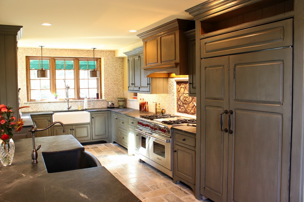 This is an example of a mid-sized traditional l-shaped eat-in kitchen in Philadelphia with a farmhouse sink, beaded inset cabinets, distressed cabinets, soapstone benchtops, with island, stainless steel appliances, porcelain floors and grey floor.