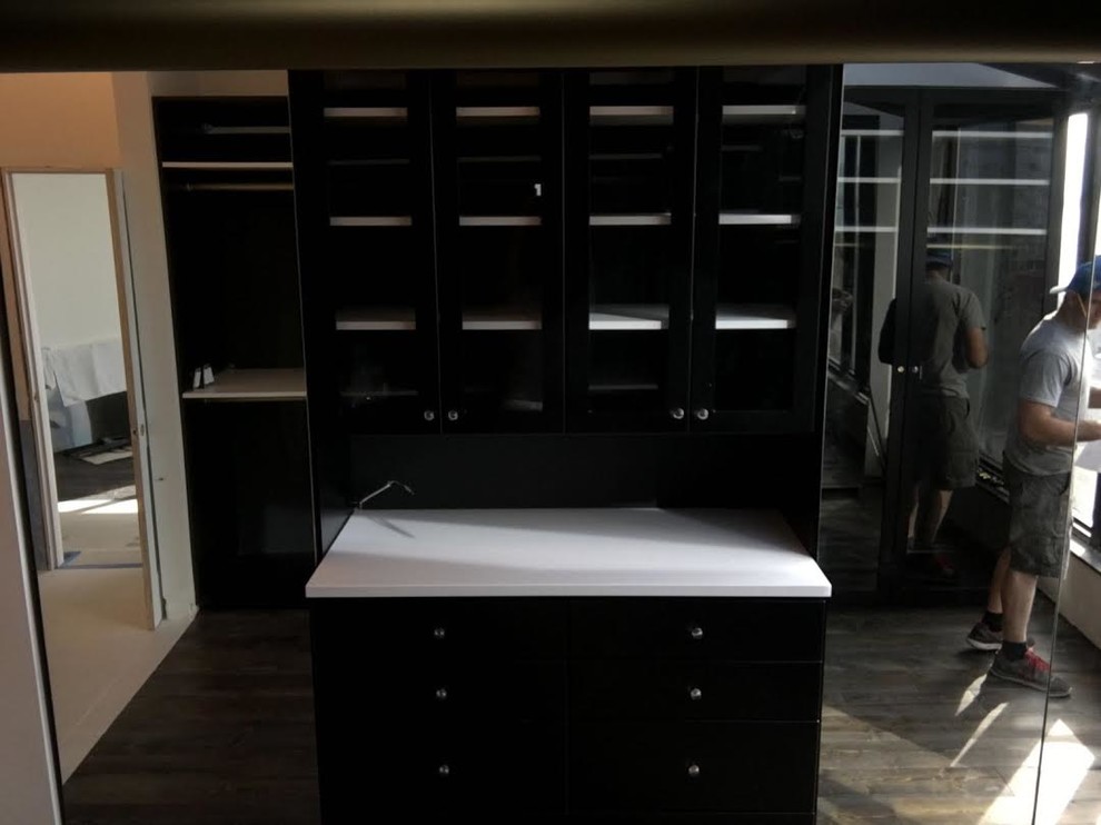 Idee per una grande cabina armadio unisex contemporanea con ante lisce, ante nere e pavimento in legno massello medio