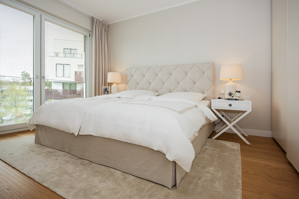 Cette image montre une chambre parentale grise et blanche design de taille moyenne avec un mur gris, parquet clair et un sol marron.