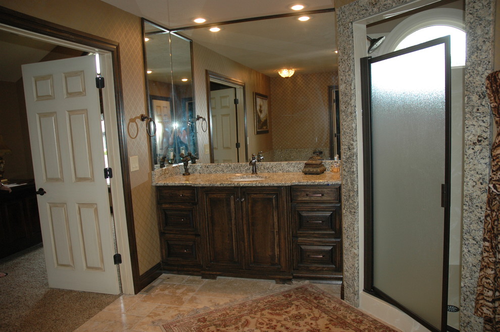 This is an example of a mid-sized country master bathroom in Other with an undermount sink, raised-panel cabinets, distressed cabinets, granite benchtops, a drop-in tub, a corner shower, a two-piece toilet, beige tile, stone tile, yellow walls and travertine floors.