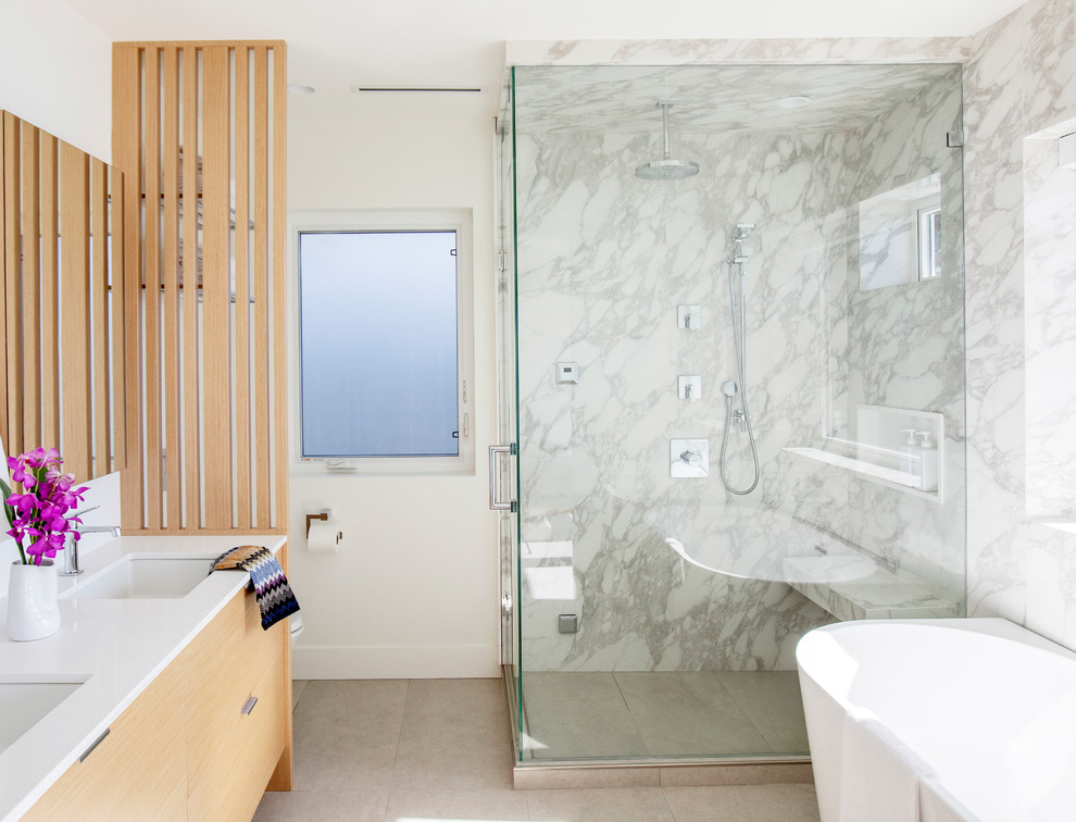 Inspiration for a mid-sized contemporary master bathroom in Vancouver with flat-panel cabinets, light wood cabinets, a freestanding tub, a corner shower, white tile, marble, white walls, porcelain floors, an undermount sink, marble benchtops, grey floor, a hinged shower door and white benchtops.