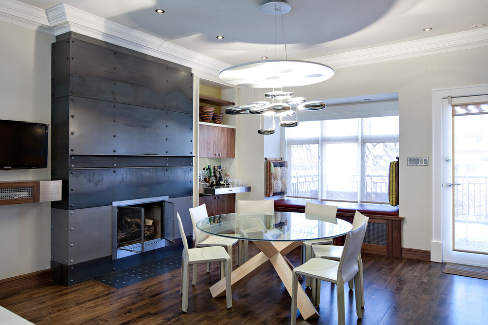 Design ideas for a contemporary dining room in Toronto with dark hardwood floors, a standard fireplace and a metal fireplace surround.
