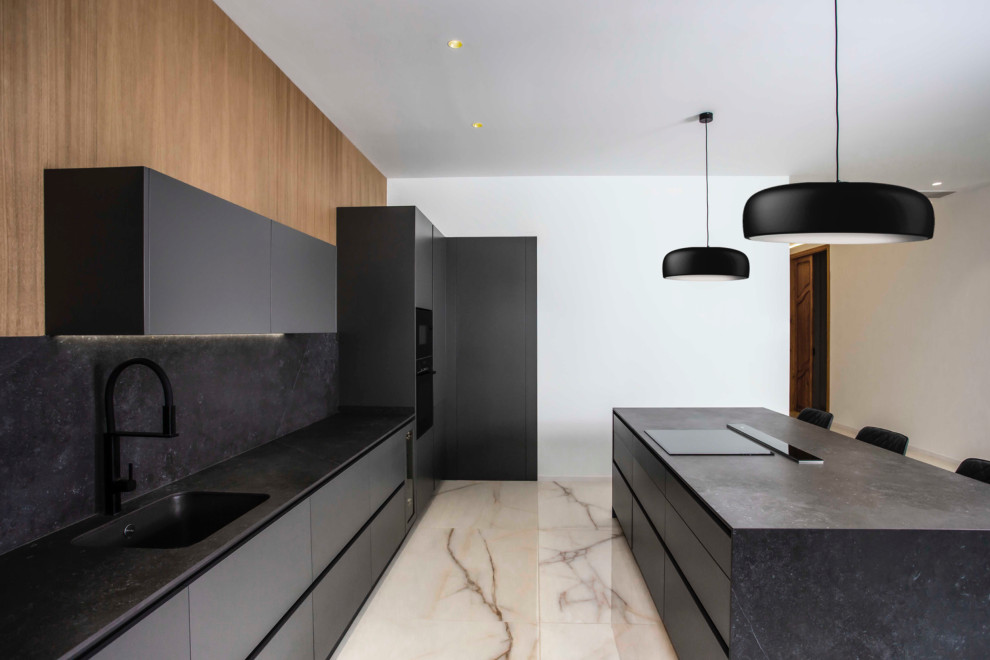 Large modern open plan kitchen in Valencia with a submerged sink, flat-panel cabinets, grey cabinets, tile countertops, grey splashback, porcelain splashback, black appliances, porcelain flooring, an island, white floors and grey worktops.