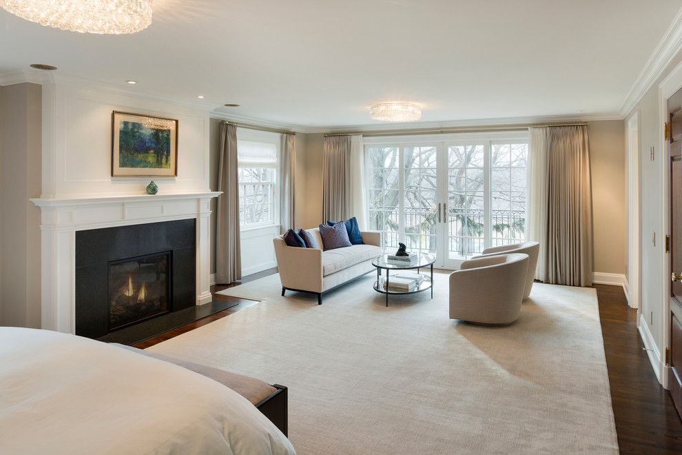 Inspiration for a mid-sized traditional master bedroom in Minneapolis with beige walls, dark hardwood floors, a standard fireplace, a plaster fireplace surround and brown floor.