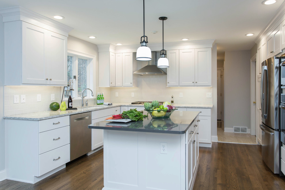 Example of a mid-sized transitional u-shaped dark wood floor enclosed kitchen design in Boston with an undermount sink, recessed-panel cabinets, white cabinets, quartz countertops, gray backsplash, subway tile backsplash, stainless steel appliances and an island