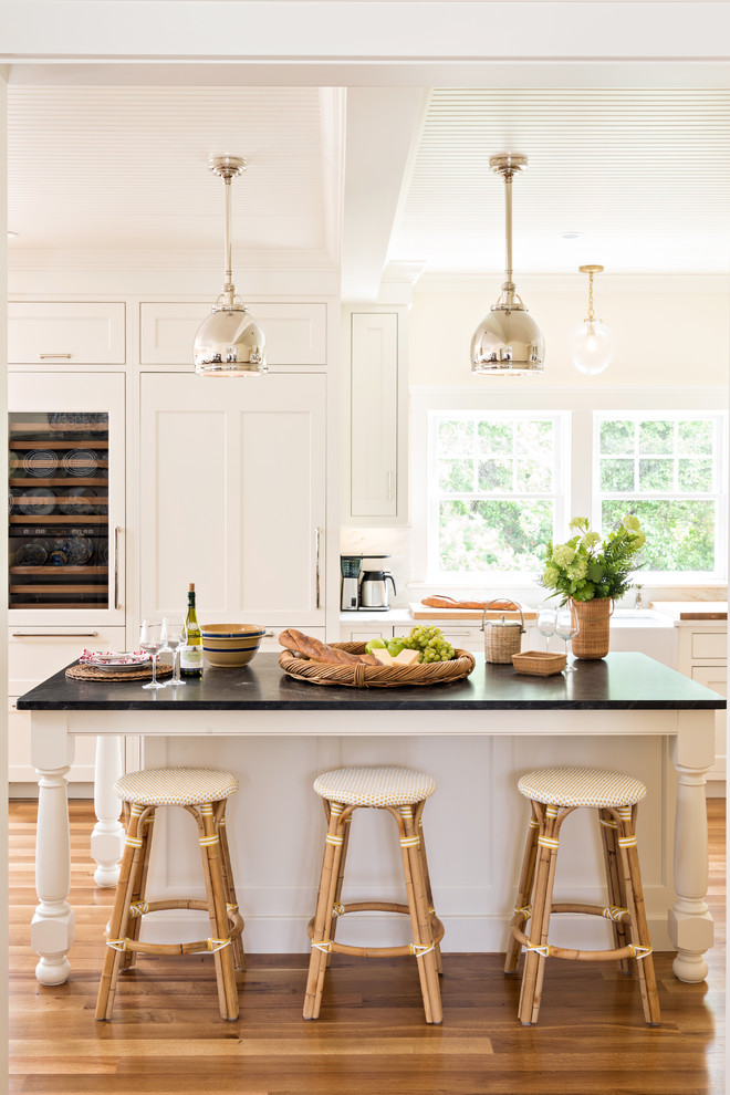 Mid-sized transitional l-shaped open plan kitchen in Boston with a farmhouse sink, beaded inset cabinets, white cabinets, marble benchtops, white splashback, stone slab splashback, panelled appliances, medium hardwood floors and with island.