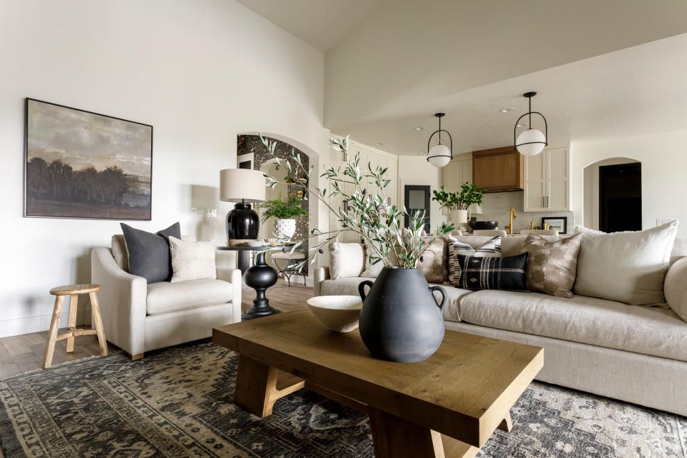 Design ideas for a large transitional open concept living room in Boise with white walls, medium hardwood floors, a standard fireplace, a stone fireplace surround, a wall-mounted tv and vaulted.