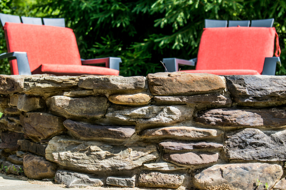 Design ideas for a rustic backyard stone landscaping in Chicago with a fire pit.