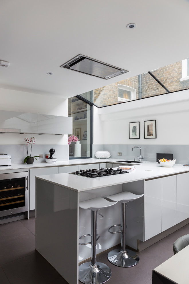 This is an example of a contemporary u-shaped eat-in kitchen in London with flat-panel cabinets, grey cabinets, grey splashback, stainless steel appliances and a peninsula.